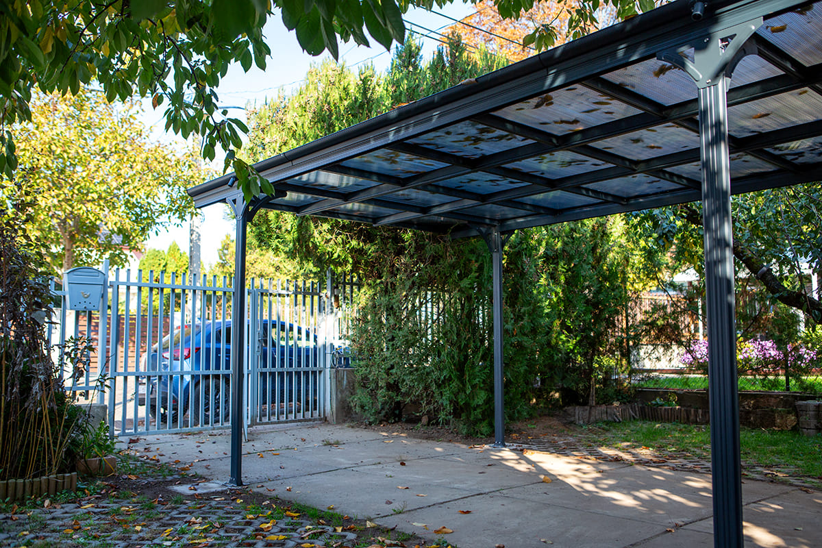 Előregyártott kocsibeálló alumínium vázzal és polikarbonát tetővel.