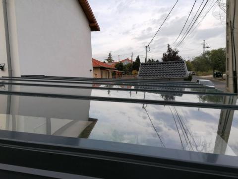 Rétegragasztott fagerenda szerkezetű autóbeálló, üveg fedéssel