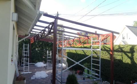 Porfestett acél tartószerkezet rácsostartóval + ragasztott biztonsági üveg fedéssel készült autóbeálló