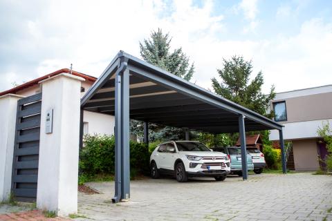 Napelemekkel fedett, extra hosszú, négy állásos kocsibeálló rétegragasztott fa szerkezettel.