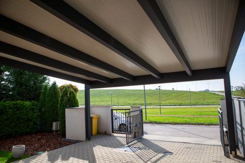 Szendvicspanel fedésű kocsibeálló, antracit színű rétegragasztott fa szerkezettel